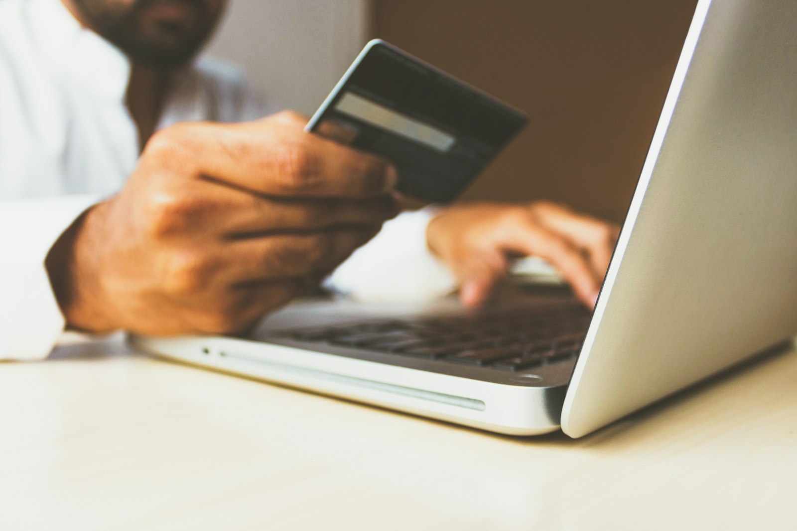 Banking app open on smartphone beside payment card and debit statement on clean office desk