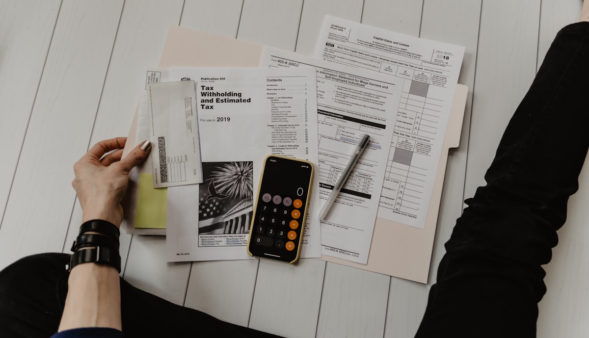 Financial documents, calculator, pen, and banking checkbooks spread on a clean office desk